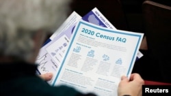 FILE - In this June 25, 2020, photo, two young children hold signs through the car window that make reference to the 2020 US Census as they wait in the car with their family at an outreach event in Dallas, Texas.