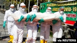 Health workers of the Indonesian police force carry a dummy as they train volunteers how to handle remains of COVID victims, at Manahan Stadium in Solo, Central Java province, Indonesia July 6, 2021. (Antara Foto/Maulana Surya/via Reuters)