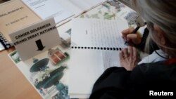 A woman writes in a book of grievances (Cahier de doleances) at the city hall on the eve of the launching of the 'Great National Debate' in Grand Bourgtheroulde, France, Jan. 14, 2019.