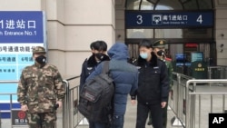 Security officers check a person at an entrance to the Hankou Railway Station in Wuhan in central China's Hubei Province, Jan. 23, 2020.