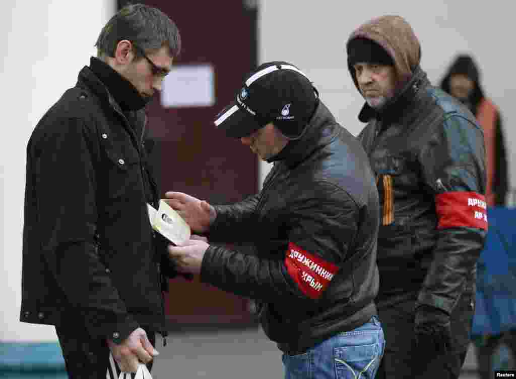 Members of a Crimean self-defense unit check the passport of a passenger at the railway station in Simferopol, Crimea, Ukraine, March 11, 2014.&nbsp;
