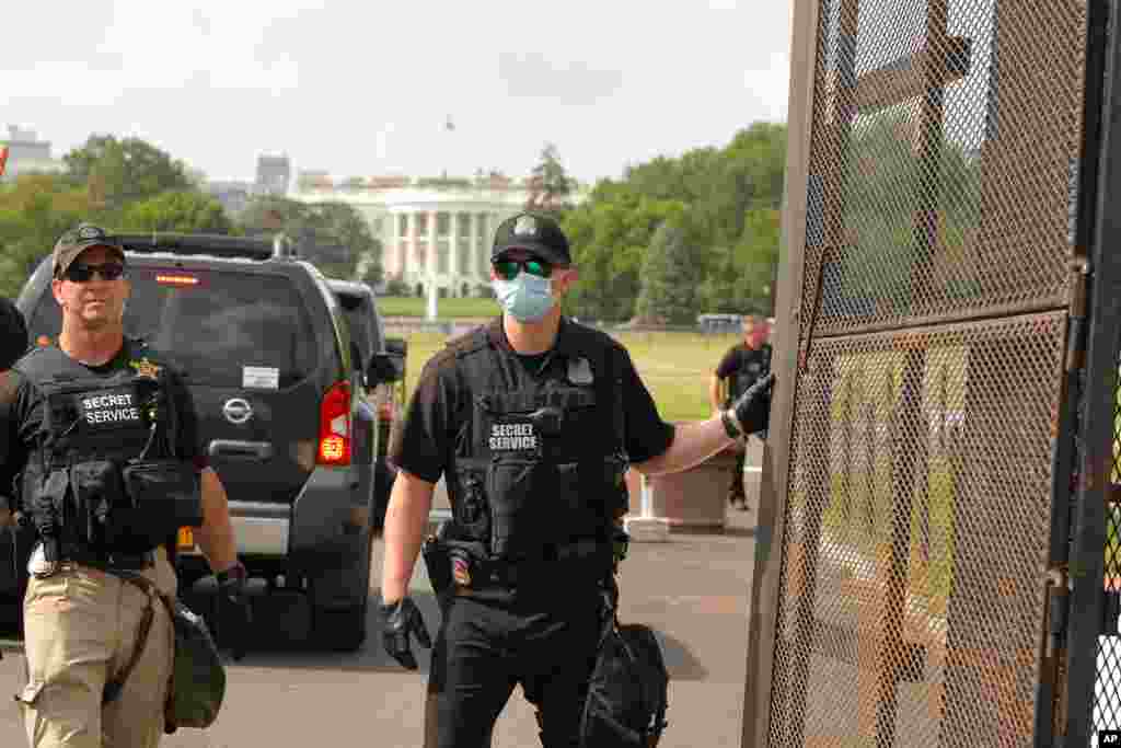 U.S. Secret Service police watch through a gate in the fence as demonstrators protest June 6, 2020, near the White House in Washington, over the death of George Floyd.