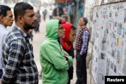 People read pages of newspapers stuck on a wall in Dhaka the morning after Bangladesh's Awami League won the 12th general election.