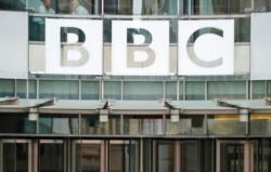 FILE - The BBC sign is seen outside the entrance to the headquarters of the publicly funded media organization in London, July 19, 2017.