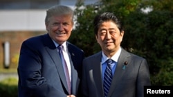 FILE - Then-U.S. President Donald Trump shakes hands with then-Japanese Prime Minister Shinzo Abe upon his arrival at the Kasumigaseki Country Club in Kawagoe, near Tokyo, Nov. 5, 2017.