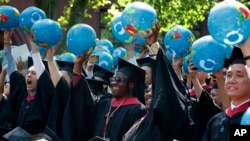 FILE - Public policy and government graduate students hold inflatable globes during Harvard University commencement exercises, Thursday, May 24, 2018, in Cambridge, Mass. (AP Photo/Michael Dwyer)