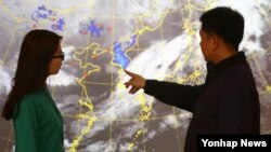 23일 한국 기상청 직원들이 천리안 위성으로 관측된 한반도의 황사를 살펴보고 있다. 푸른색으로 표시된 부분은 황사를 나타내고, 붉은 점은 중국에서 황사가 관측된 지점을 나타낸다.