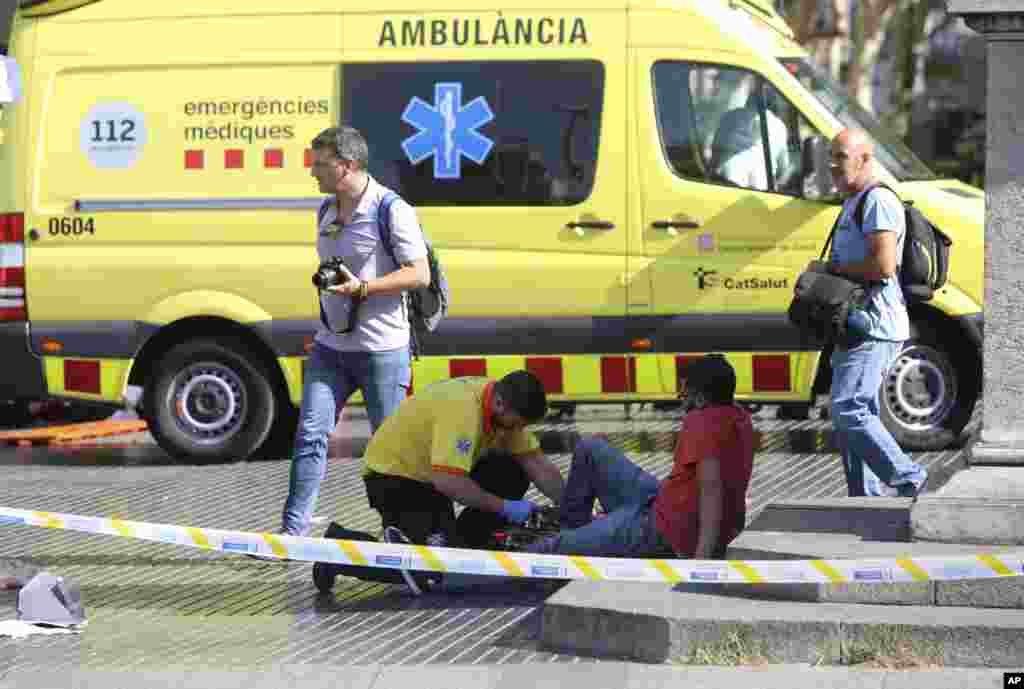 Wani da ya samu rauni bayan harin ta addanci na 17 ga watan Agusta na shekar 2017 na samun taimako daga yan sanda. An injured person is treated in Barcelona, Spain, Aug. 17, 2017 after a white van jumped the sidewalk in the historic Las Ramblas district, crashing into a summer crowd of residents and tourists.