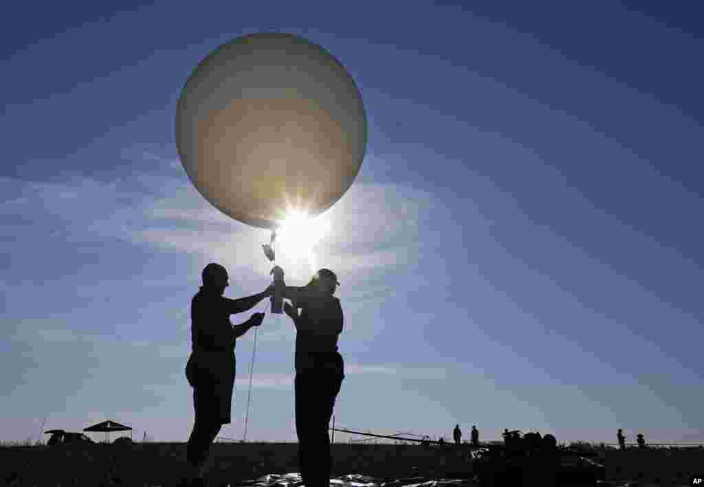 Mike Newchurch, left, professor of atmospheric chemistry at the University of Alabama in Huntsville, and graduate student Paula Tucker prepare a weather balloon before releasing it to perform research during the solar eclipse, Aug. 21, 2017, on the Orchar