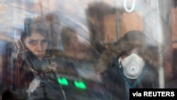 An Iranian woman wears a protective mask to prevent contracting coronavirus, as she sits in the bus in Tehran, Iran, Feb. 25, 2020.