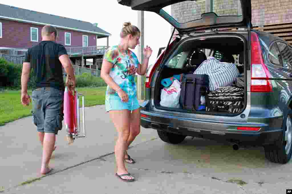 Nicole Specht dan Ryan Witman mengepak barang di bagasi Honda CRV mereka sebelum kembali ke rumah di Lancaster, Pennsylvania karena evakuasi wajib di Rodanthe, North Carolina (3/7).(AP/Jerome Bailey Jr.)
