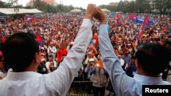 លោក សម រង្ស៊ី និង​លោក​ កឹម សុខា ចាប់​ដៃ​ ខណៈ​ដែល​អ្នក​គាំទ្រ​សាទរ​នៅ​ទី​លាន​ប្រជាធិបតេយ្យ​នៅ​កណ្តាល​ក្រុង​ភ្នំពេញ​កាល​ពី​ថ្ងៃ​ទី​១៦ ខែ​ធ្នូ ឆ្នាំ​២០១៣។