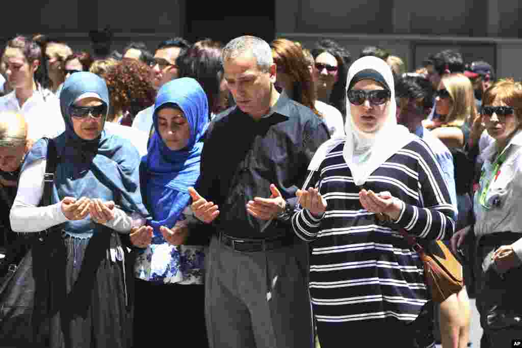 Sydney Muslim community leader Jamal Rifi, center, and his family members pray at a makeshift memorial after a siege at Martin Place in the central business district of Sydney, Australia Tuesday, Dec. 16, 2014.