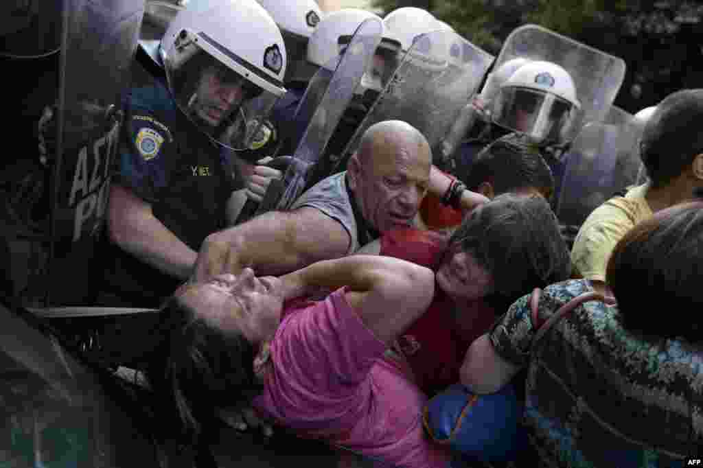 Cleaners laid-off by the Finance Ministry are pushed back by riot police in their attempt to protest outside the ministry in Athens, Greece.