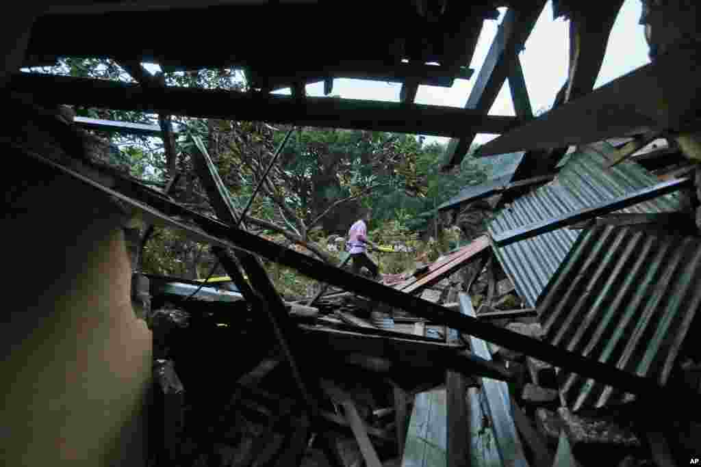 Sri Lankans walk past a damaged house at the site of a mudslide at the Koslanda tea plantation in the Badulla district, Sri Lanka, Oct. 29, 2014. 