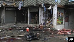 An Afghan security forces member inspects at the site of a suicide attack near a bank in Jalalabad, east of Kabul, Afghanistan, April 18, 2015. 