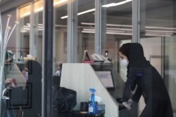FILE - A stock market employee wearing a protective face mask and gloves looks at a screen displaying stock prices at Tehran Stock Exchange, following the outbreak of the coronavirus disease, in Tehran, Iran, May 12, 2020.