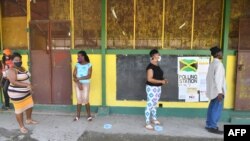 Masked voters stand in line before casting their ballots in Jamaica's St. Catherine north central constituency during the general election, September 3,2020.