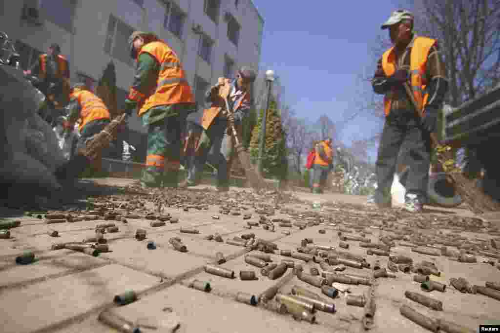 Street cleaners sweep away bullet cases as they remove trash and a barricade erected by pro-Russian protesters near a building of the state security service in Donetsk, Ukraine, April 8, 2014.