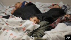 FILE - This June 18, 2014, file photo shows children detainees sleeping in a holding cell at a U.S. Customs and Border Protection processing facility in Brownsville,Texas. 