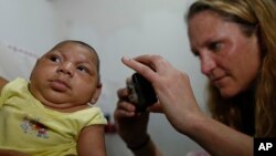 Pediatrician Alexia Harrist from the United States' Centers for Disease Control and Prevention (CDC) takes a picture of 3-month-old Shayde Henrique who was born with microcephaly, after examining him in Joao Pessoa, Brazil, Tuesday, Feb. 23, 2016. In its