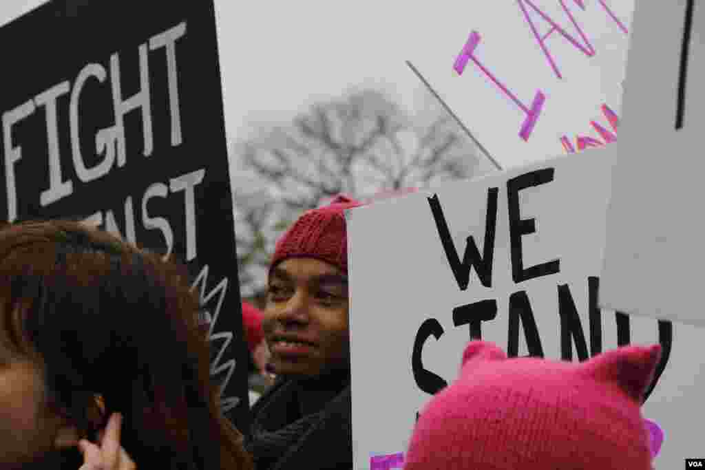 A woman sporting a pink hat marches with hundreds of thousands of others holding signs in Washington, D.C., Jan. 21, 2017. (E. Sarai/VOA)