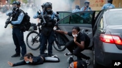 អ្នក​បើក​បរ​រថយន្ត​ត្រូវ​ប៉ូលិស​បញ្ជា​ឲ្យ​ចេញ​ពី​រថយន្ដ​របស់​ខ្លួន​​ហើយ​ក្រាប​ទៅ​នឹង​ដី ក្នុង​អំឡុងពេល​តវ៉ា​ករណី​ស្លាប់​របស់​លោក George Floyd នៅ​ក្នុង​ក្រុង Minneapolis សហរដ្ឋអាមេរិក ថ្ងៃ​ទី​៣១ ខែឧសភា ឆ្នាំ​២០២០។ (AP Photo/John Minchillo)