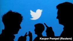 Siluet para pengguna ponsel dengan latar belakang logo Twitter di Warsawa, 27 September 2013.