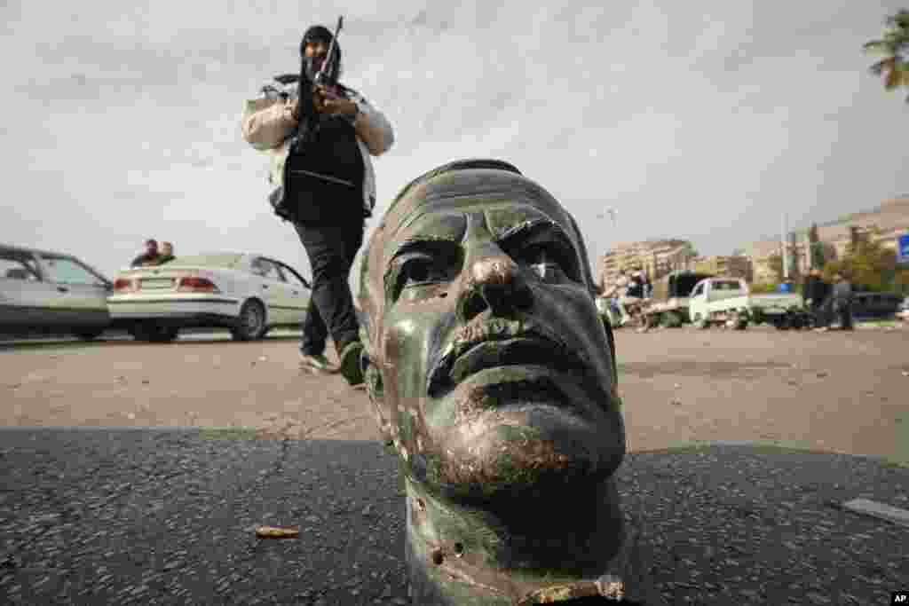 An opposition fighter walks beside a broken bust of the late Syrian President Hafez Assad in Damascus, Dec. 8, 2024.