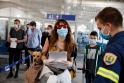 A firefighter directs passengers who arrived from Rome, Italy to the Eleftherios Venizelos International Airport in Athens, June 15, 2020.
