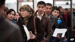 FILE - Migrants stand in line to register at Moscow's migration center in Sakharovo, a village about 60 kilometers (35 miles) south of Moscow, Russia, April 22, 2015. 