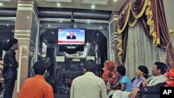 Yemenis watch a TV broadcasting an audio broadcast of Yemeni President Ali Abdullah Saleh, in a hotel in Taiz, Yemen, Friday, June 3, 2011
