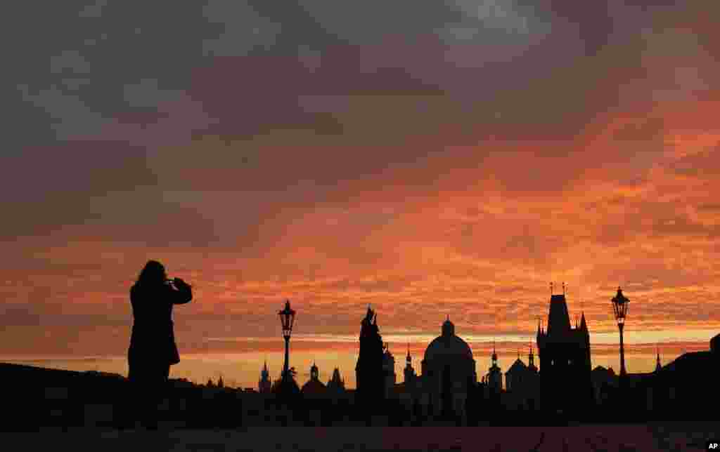 Seorang perempuan memotret suasana di 'Charles Bridge' saat matahari terbit di kota Praha, Republik Ceko.