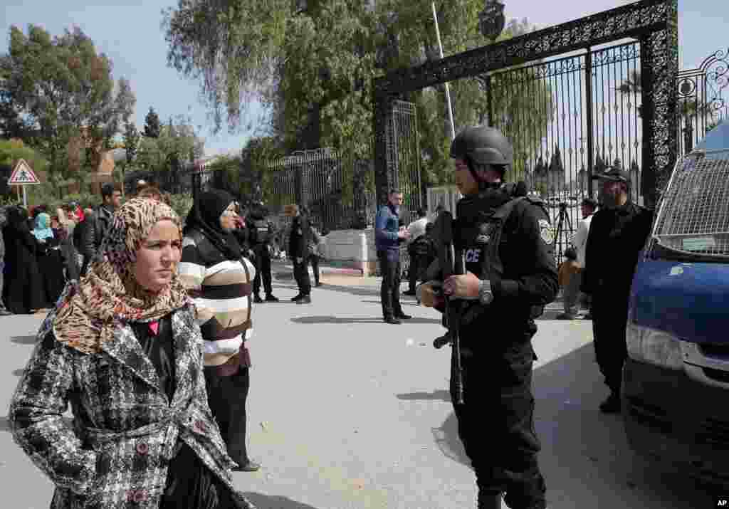 Bystanders watch as policemen guard the Bardo museum, in Tunis, Tunisia, March 19, 2015.