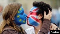 Two activists with the EU flag and Union Jack painted on their faces kiss each other in front of Brandenburg Gate to protest against the British exit from the European Union, in Berlin, Germany, June 19, 2016.
