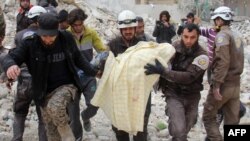 FILE - Members of the Syrian civil defense, known as the White Helmets, remove a victim from the rubble of a destroyed building following a reported airstrike in the northwestern city of Idlib, March 15, 2017.
