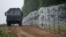 FILE - A view of a vehicle next to a fence built by Polish soldiers on the border between Poland and Belarus is seen near the village of Nomiki, Poland, Aug. 26, 2021.