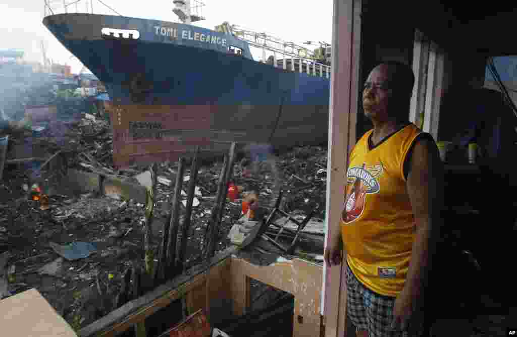 Penyintas topan Manolito Pacurib berdiri di dalam rumahnya yang hancur dekat kapal yang terdampar ke pantai akibat Topan Haiyan di Tacloban, Filipina (23/12). (AP/Achmad Ibrahim)