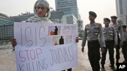 Anggota kepolisian tengah mengamati seorang pria yang membentangkan poster menentang kelompok militan ISIS dalam sebuah aksi protes di Jakarta (15/9).