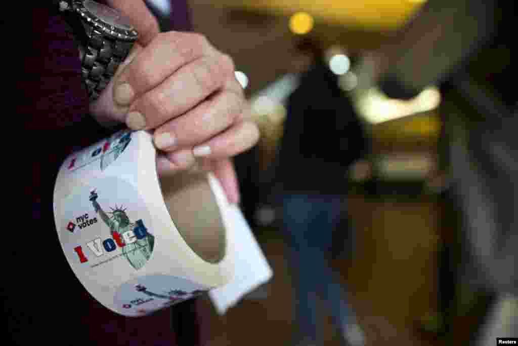 A door clerk waits to hand stickers to voters after they cast their votes for the New York Mayoral Election at the Congregation Mount Sinai in New York, Nov. 5, 2013.