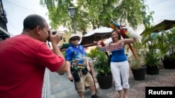 FILE - Tourist Cindy Huyzen poses for her husband, Michael Huyzen, while visiting San Juan, Puerto Rico, July 19, 2015.