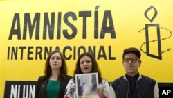 Madeleine Penman, left, Mexico investigator for Amnesty International; Erika Guevara-Rosas, center, Americas Director for Amnesty; center, and Byron Arellano, son of a torture survivor, pose together following a press conference presenting an Amnesty report on female survivors of sexual torture by Mexican authorities, in Mexico City. (AP Photo/Rebecca Blackwell)