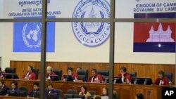 FILE - In this Oct. 19, 2011 file photo released by the Extraordinary Chambers in the Courts of Cambodia, court officers of the U.N.-backed war crimes tribunal are seen through windows during a hearing of former Khmer Rouge top leaders in Phnom Penh, Cambodia.