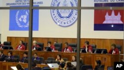Court officers of the U.N.-backed war crimes tribunal are seen through windows during a hearing of former Khmer Rouge top leaders in Phnom Penh, Cambodia.