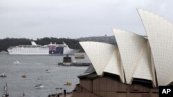 FILE - A cruise ship hangs a large national flag in celebration of Australia National Day, in Sydney Harbour behind the Opera House in Sydney.