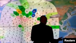 Seorang karyawan perusahaan satelit komunikasi Inmarsat menunjukkan peta pelanggan yang menggunakan jasa satelitnya dari seluruh dunia, di kantor pusat Inmarsat di London, 25 Maret 2014 (Foto: dok).