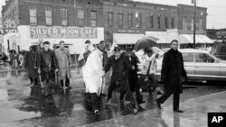 Dr. Martin Luther King Jr. hops over a puddle as it rains in Selma, Alabama. He led hundreds of African Americans to the courthouse in a voter registration drive, March 1, 1965.