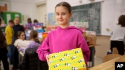 Sajra, 10, poses for a photo with a holiday present prepared for Ukrainian children inside Safvet Beg Basagic elementary school in Sarajevo, Bosnia, Tuesday, Dec. 20, 2022. (AP Photo/Armin Durgut)