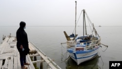Aminata Traoure, une réfugiée ivoirienne de 28 ans qui a survécu à un naufrage début mars alors qu'elle tentait de rejoindre l'Europe, regarde un bateau dans la ville côtière tunisienne de Sfax, à environ 270 km au sud-est de la capitale, le 22 avril 2021