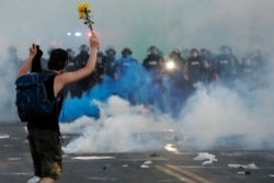 Police move towards a protester after curfew Saturday, May 30, 2020, in Minneapolis.